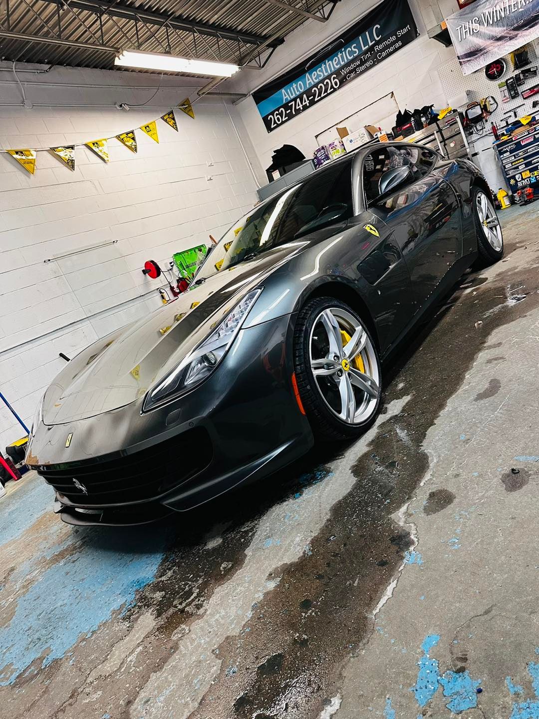 A gray ferrari is parked in a garage.