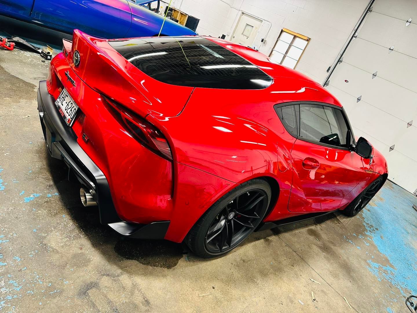 A red sports car is parked in a garage.
