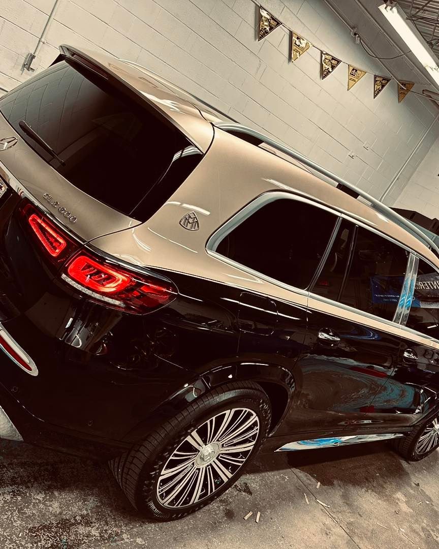 A black suv is parked in a garage next to a wall.