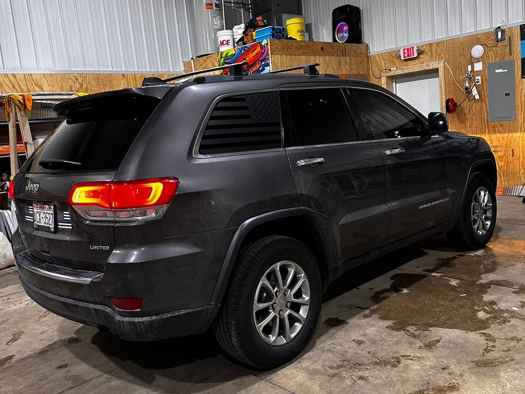 A gray jeep grand cherokee is parked in a garage.