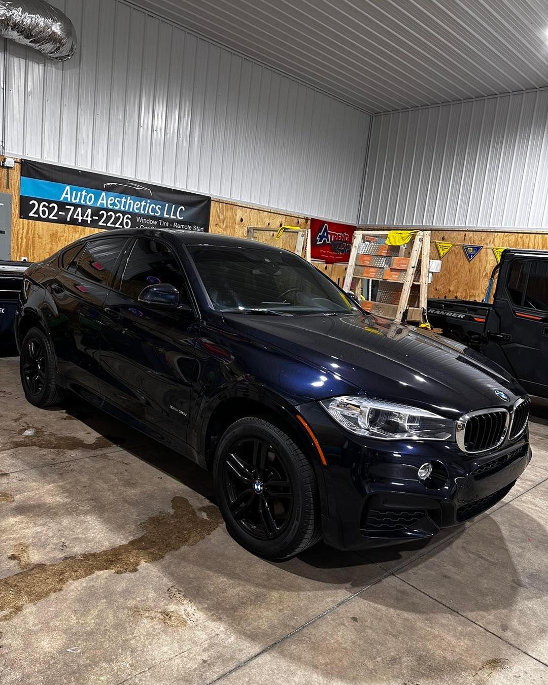 A black bmw x6 is parked in a garage.