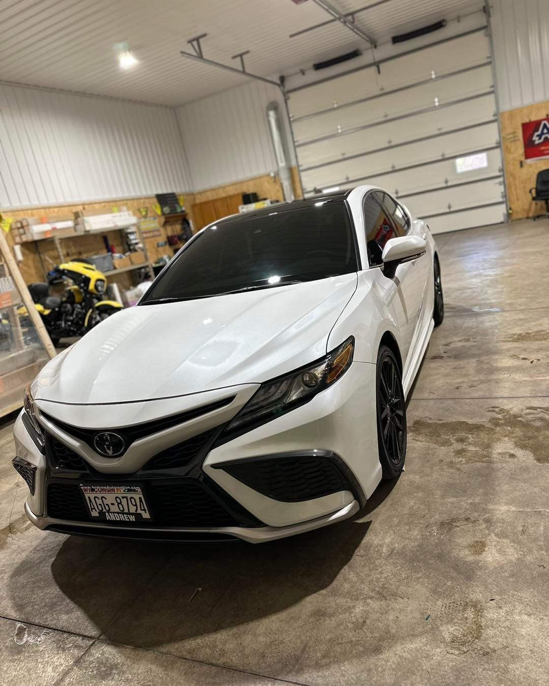 A white car is parked in a garage next to a garage door.