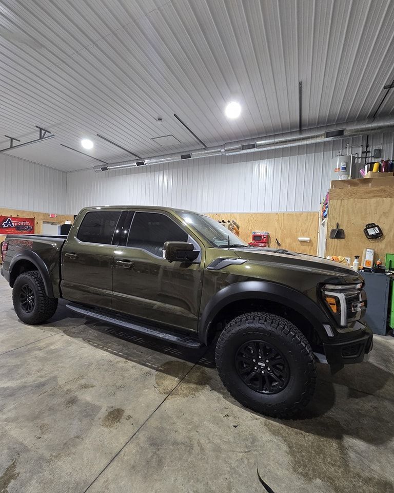 A green pickup truck is parked in a garage.