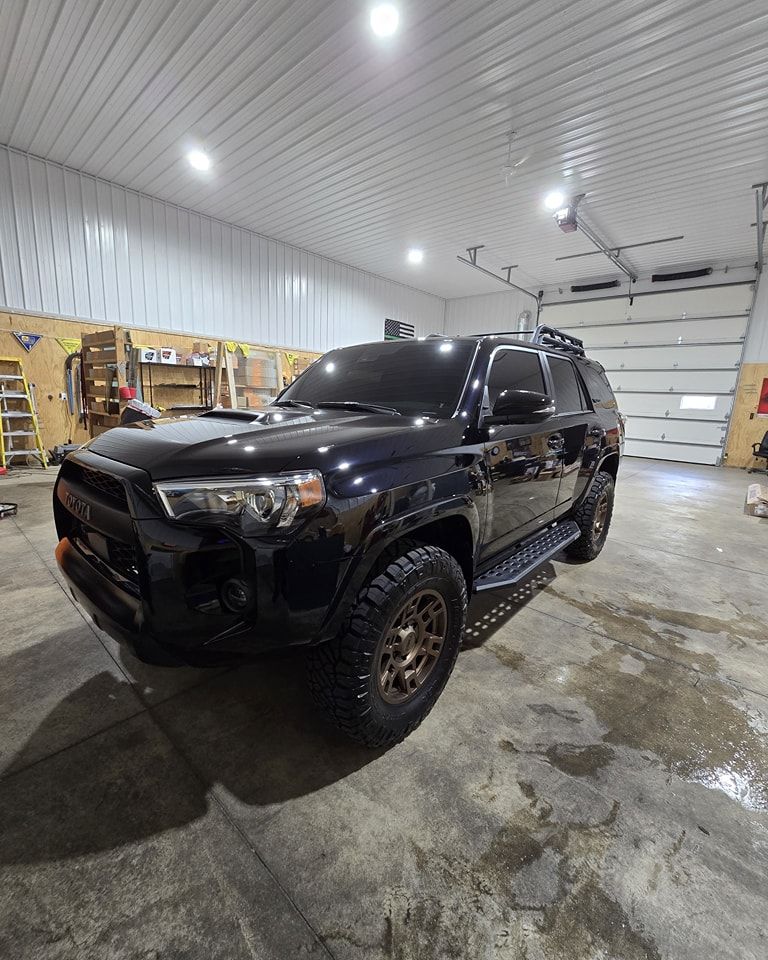 A black toyota 4runner is parked in a garage.