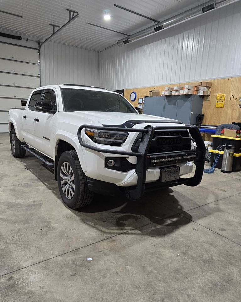 A white toyota tacoma is parked in a garage.