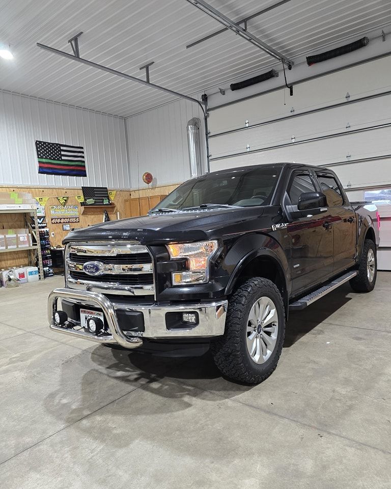 A black ford f150 truck is parked in a garage.