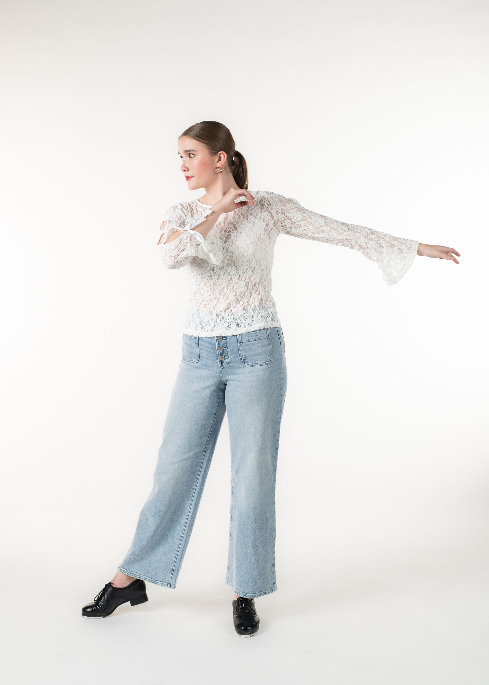 Woman in jeans and lace top, gesturing to her left, looking in the same direction.