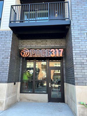 Entrance to Pace 317 with signage above the door and a small balcony above. Dark brick on the building's exterior.