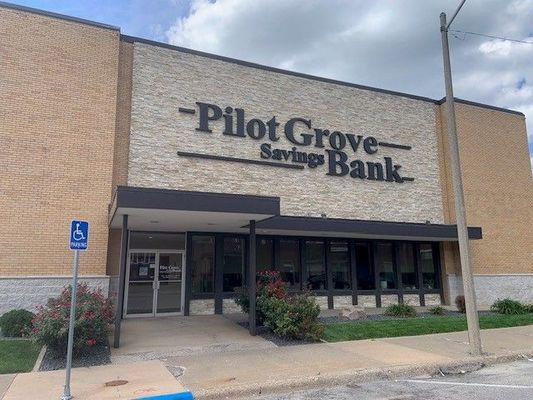 Pilot Grove Savings Bank building, tan brick exterior, black trim, sign above entrance, accessible parking sign.