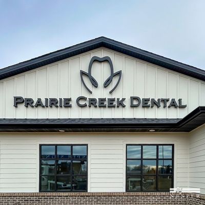 Exterior of Prairie Creek Dental office building with logo and windows.