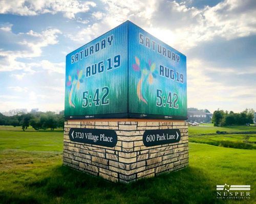 Signpost with date (Saturday, Aug 19), time (5:42), and street names in a grassy field.