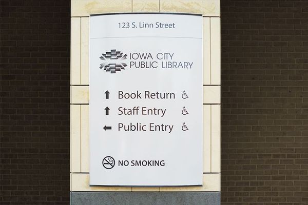 Sign for Iowa City Public Library with directional arrows and no smoking symbol.