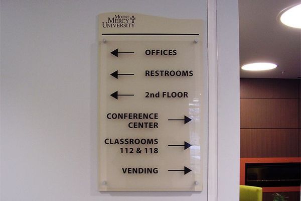 Sign with directional arrows for offices, restrooms, 2nd floor, conference center, classrooms, and vending; Mercy University logo at top.