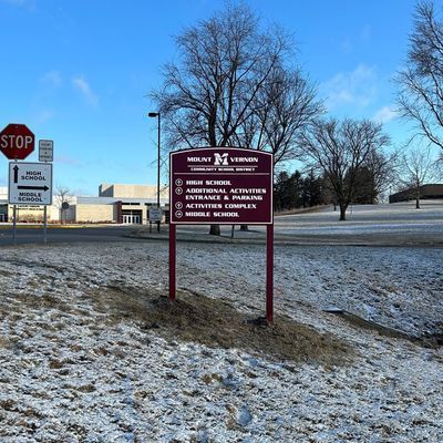 Sign for Mount Vernon Community School District with snowy ground and buildings.