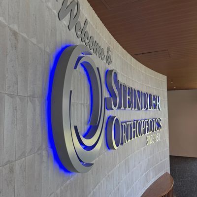 Welcome sign for Steindler Orthopedics with blue neon lighting on a curved wall.