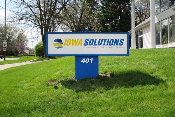 Sign for Iowa Solutions, blue and white, with address 401 on a grassy lawn.