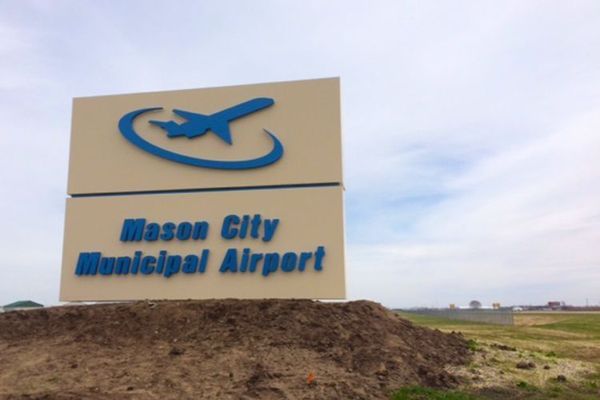 Sign for Mason City Municipal Airport, featuring a blue airplane graphic and text.