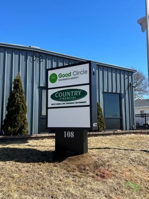 Sign for Good Circle Dermatology and Country Financial at 108 with a blue building in the background.