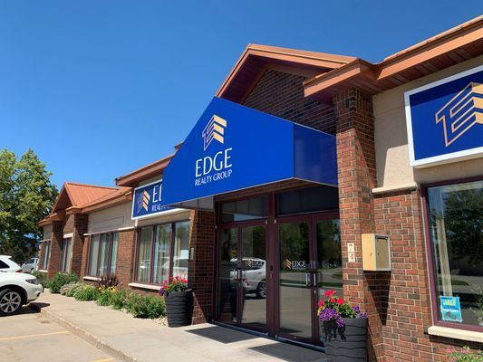 Blue awning over entrance to EDGE Realty Group office; brick exterior; sunny day.