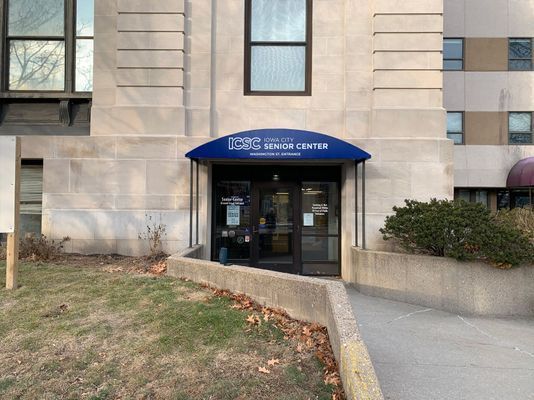 Exterior of senior center with blue awning over glass door entrance.