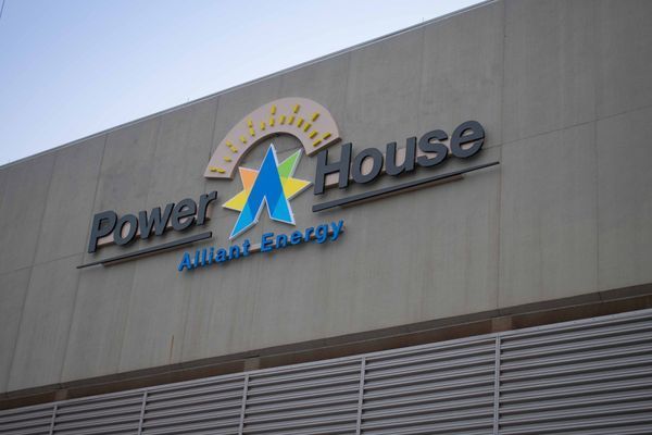 Power House building sign with logo: blue, yellow, and silver text on a gray wall. 