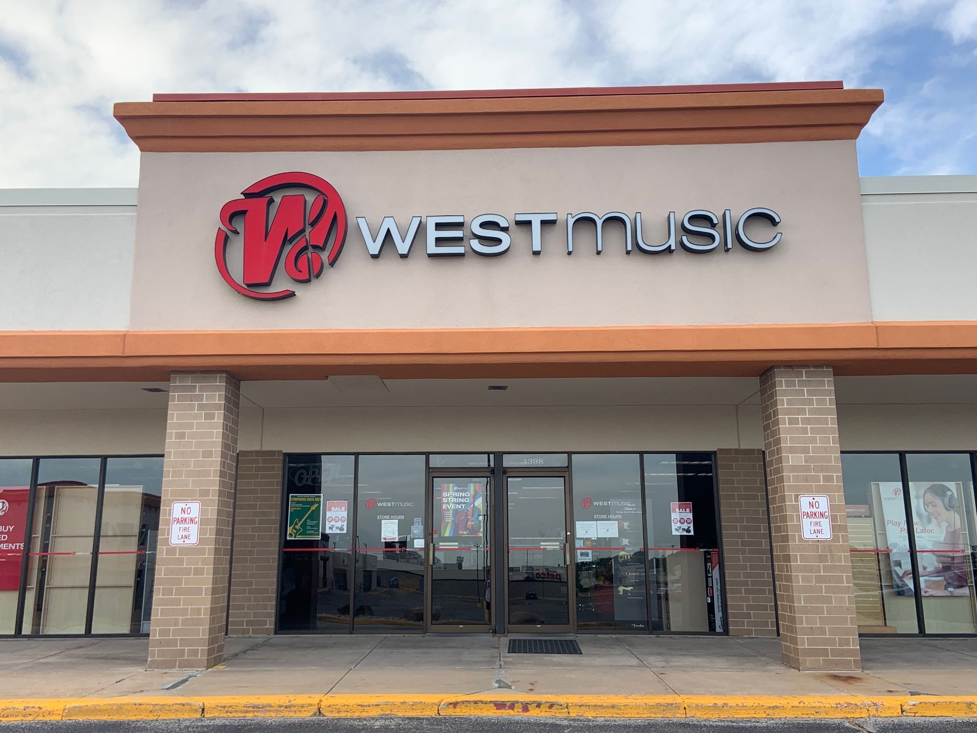 Exterior of West Music store with red logo on tan building and glass doors.