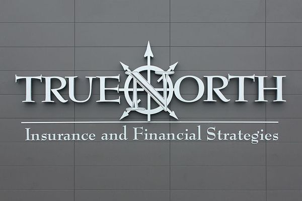 True North Insurance sign on a gray building; features a compass rose graphic, and the company's name and services.