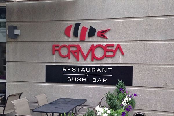 Formosa Restaurant & Sushi Bar sign with stylized fish logo. Red and black on a tan building.