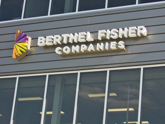 Signage for Berthel Fisher Companies on building exterior. Includes logo in shades of orange, yellow, and purple.