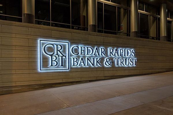 Illuminated sign for Cedar Rapids Bank & Trust on a building's exterior.