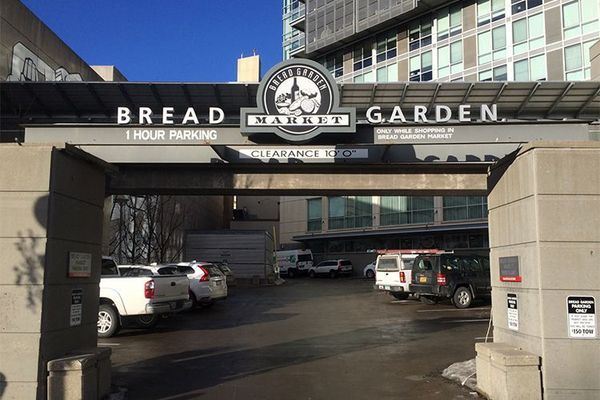 Entrance to Bread Garden restaurant with parking; several cars parked beneath a sign.