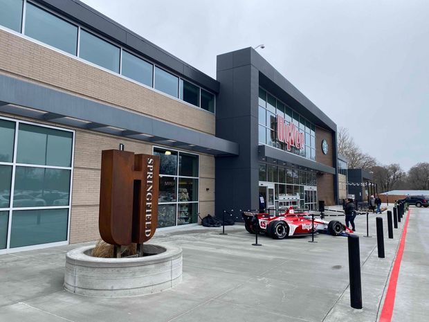 Exterior of Springfield building with a race car on display. "Springfield" sign in front. Gray sky.
