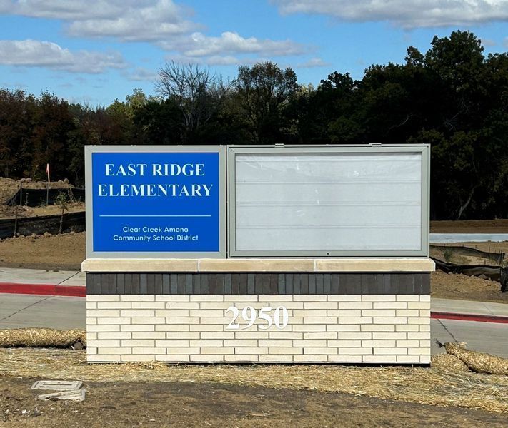 Sign for East Ridge Elementary, with address 2950, and message board, in front of a blue sky and trees.