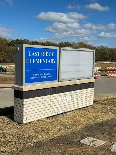 Sign for East Ridge Elementary, blue and white text on a brick and stone structure. Sunny day.