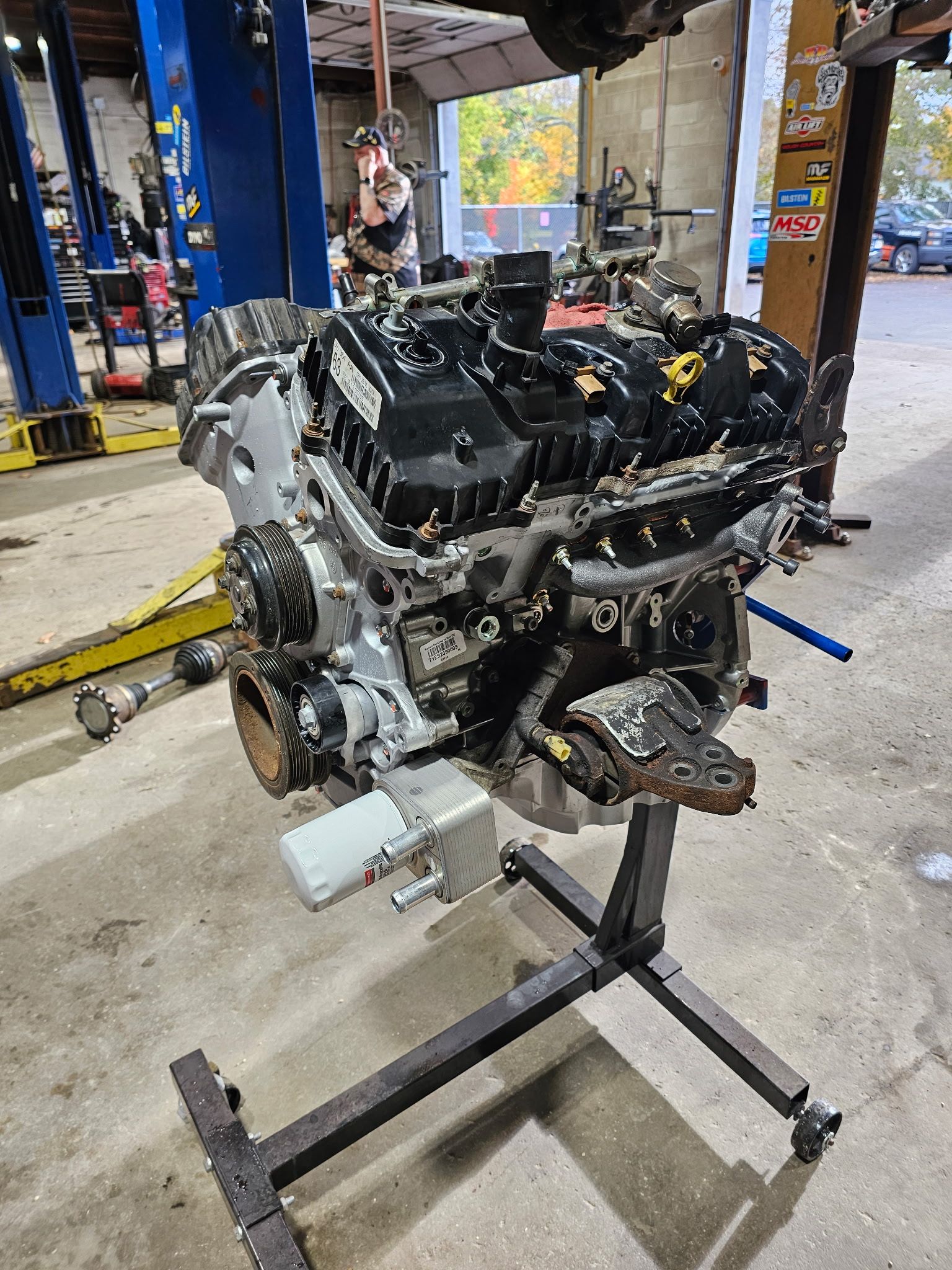 Car engine on a stand in an auto repair shop, with tools and a lift in the background