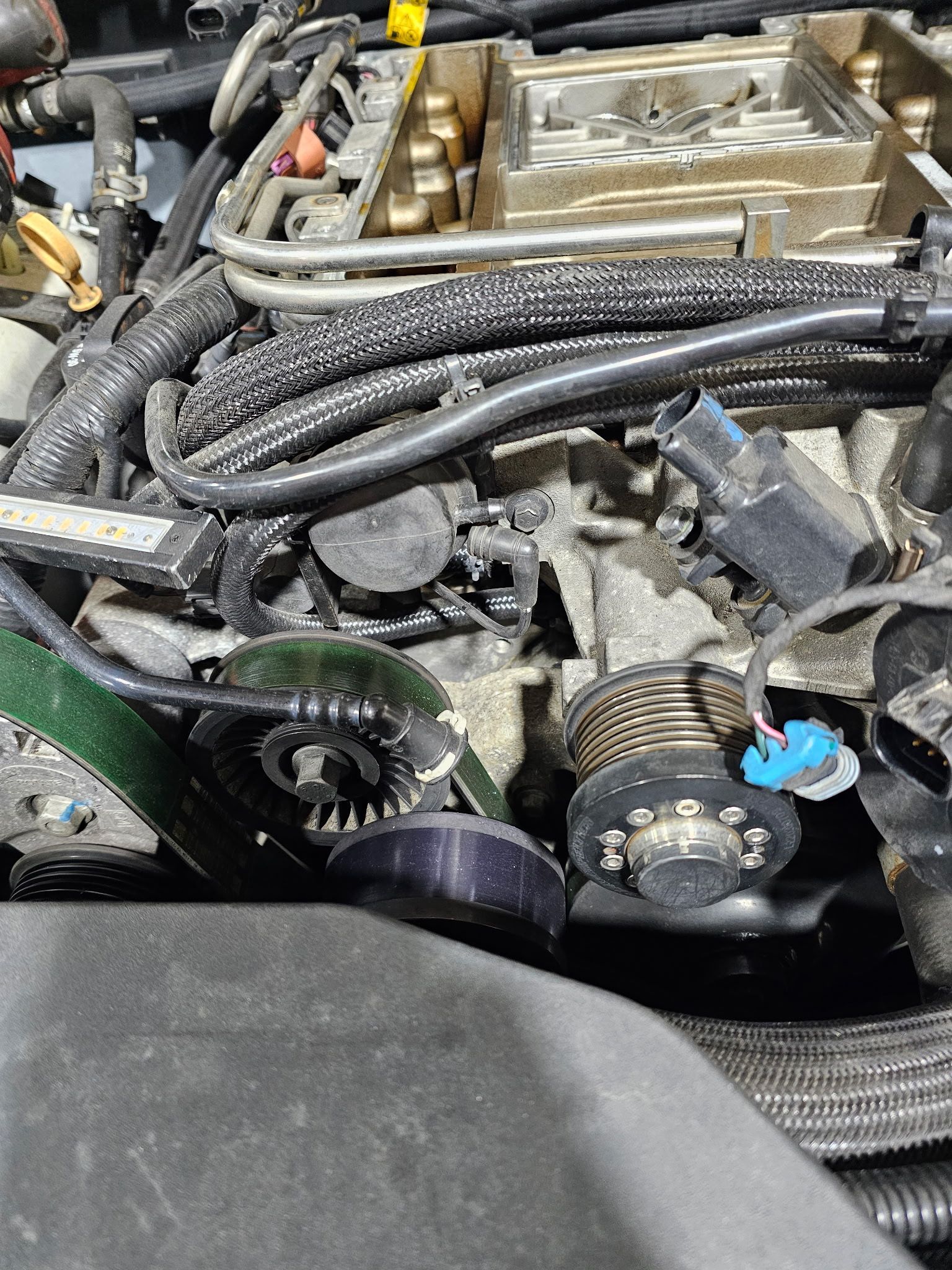 Close-up of a car engine with belts, hoses, and wiring under the hood