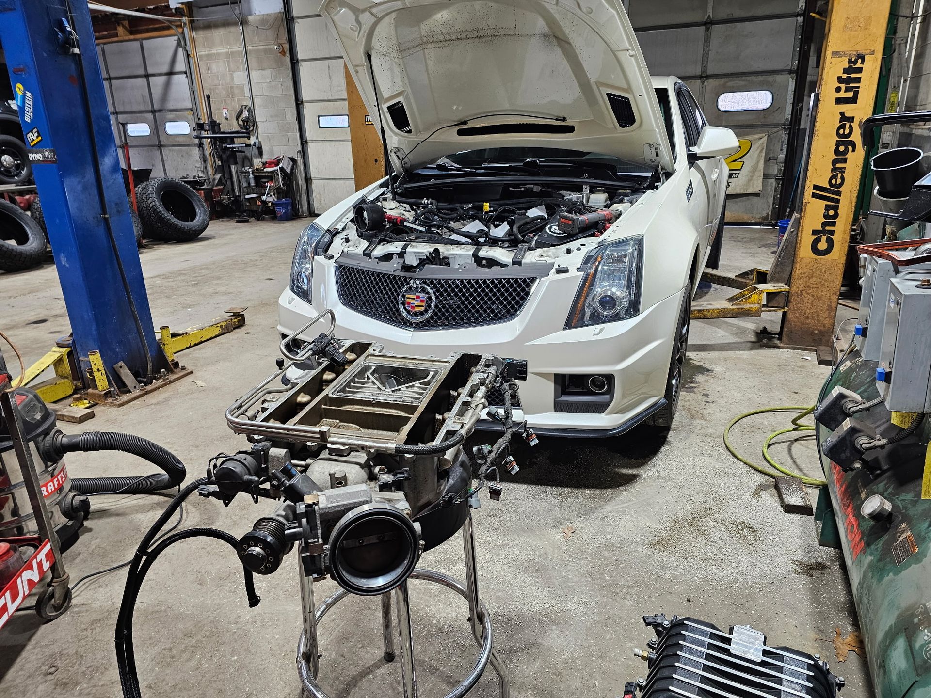 White Cadillac in auto shop with front end removed and engine exposed