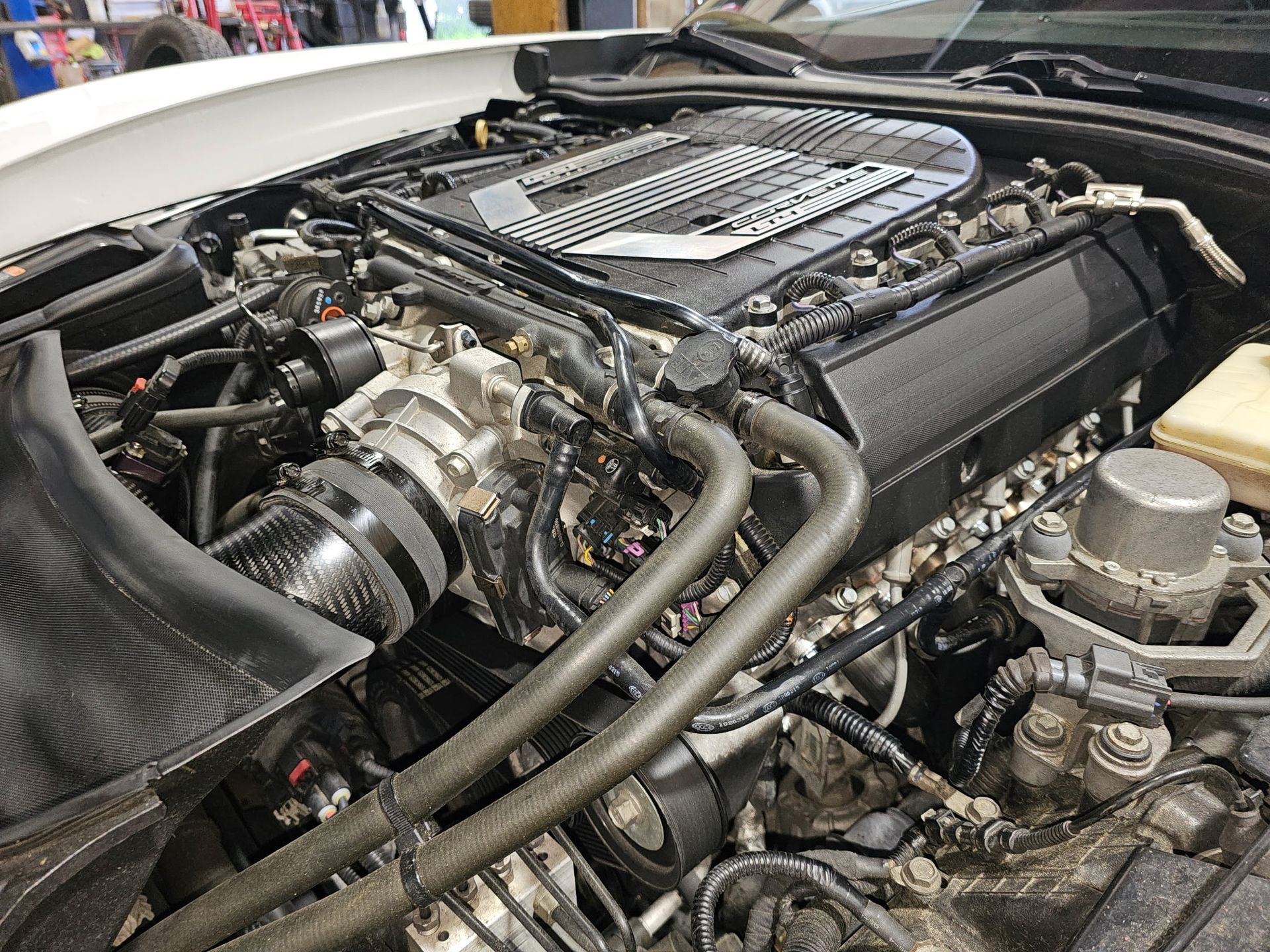 Car engine bay with exposed intake and hoses, showing the engine cover and mechanical components.