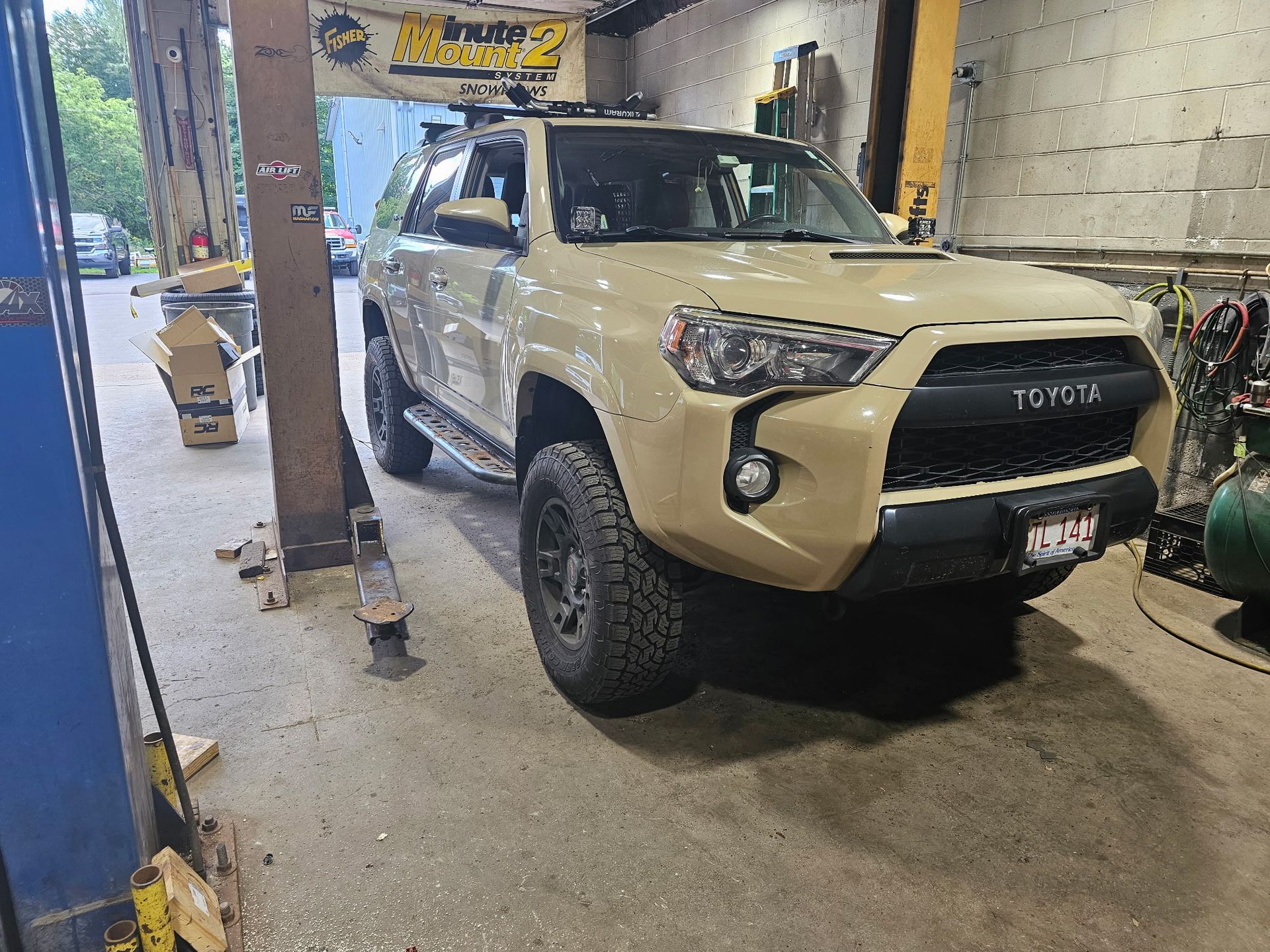 Beige Toyota SUV parked inside a garage beside a metal support pillar.