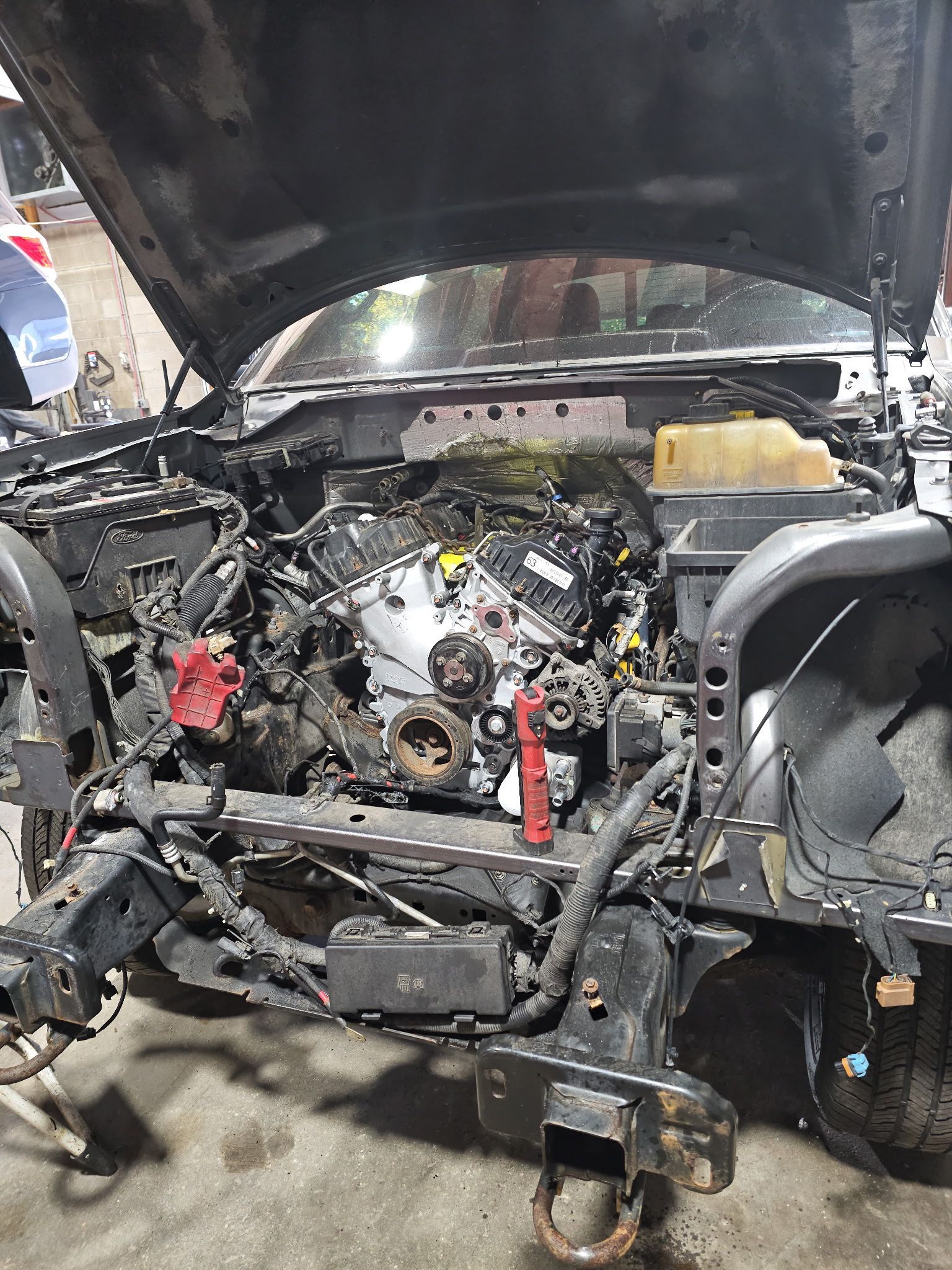 Close-up of a car engine compartment with belts, hoses, and a central intake component