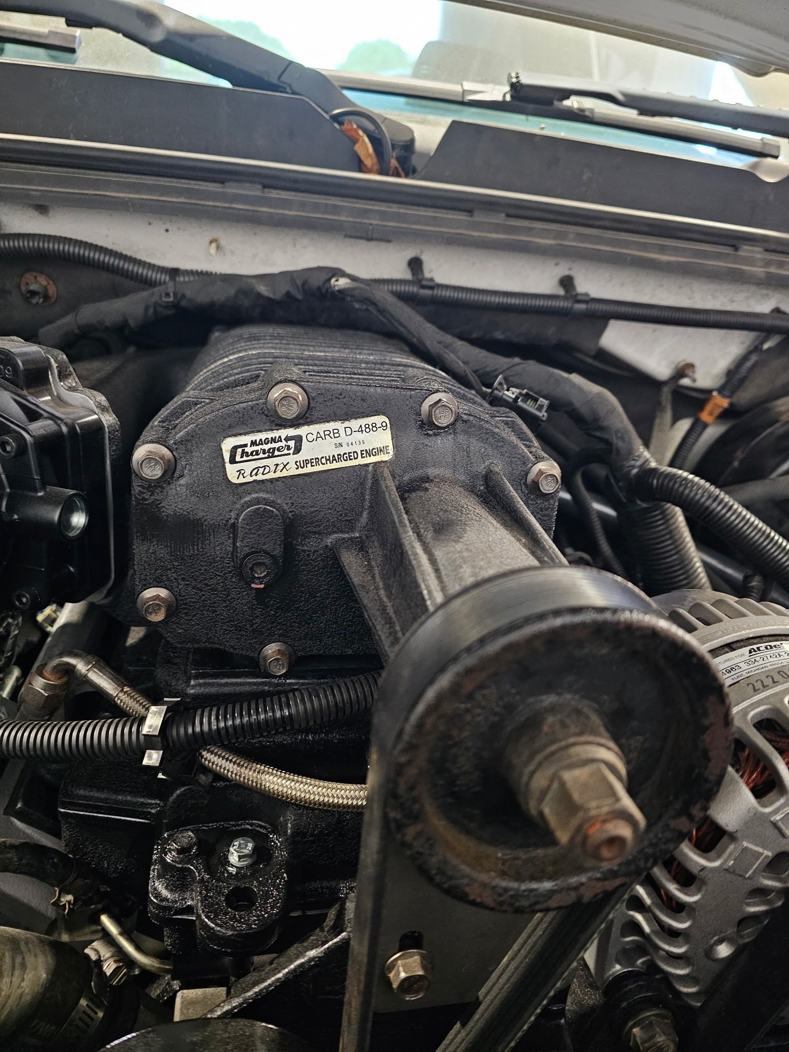 Car engine with exposed intake and belts inside the hood compartment