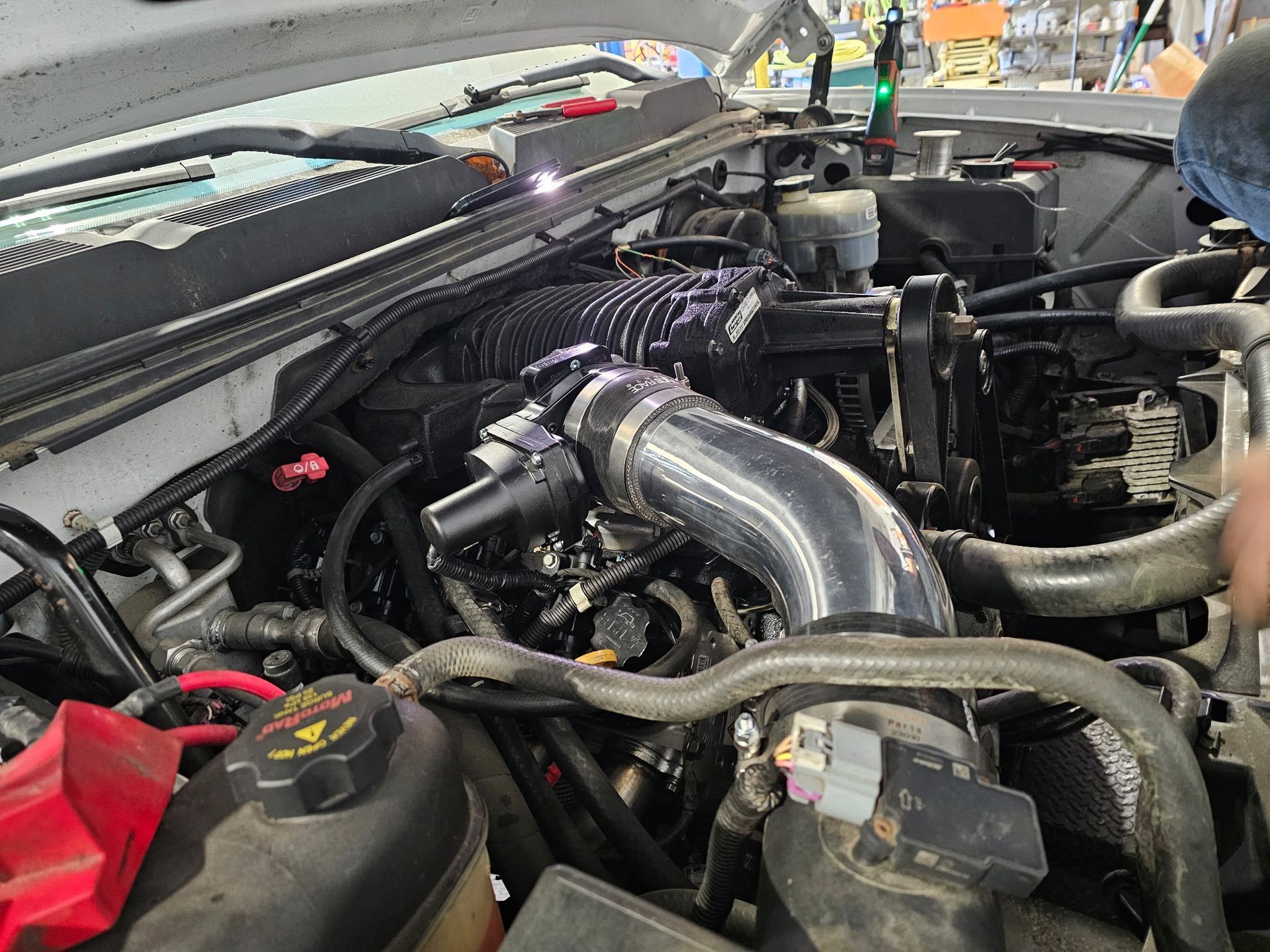 Car engine bay with polished intake piping and exposed turbo components in a workshop.
