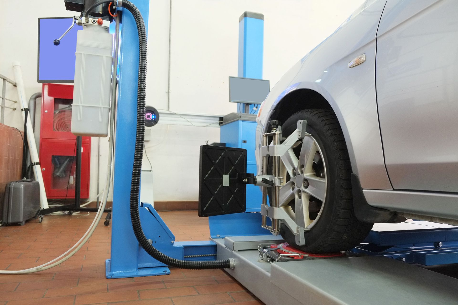 Car on a blue alignment lift in an auto repair shop, with wheel sensors attached