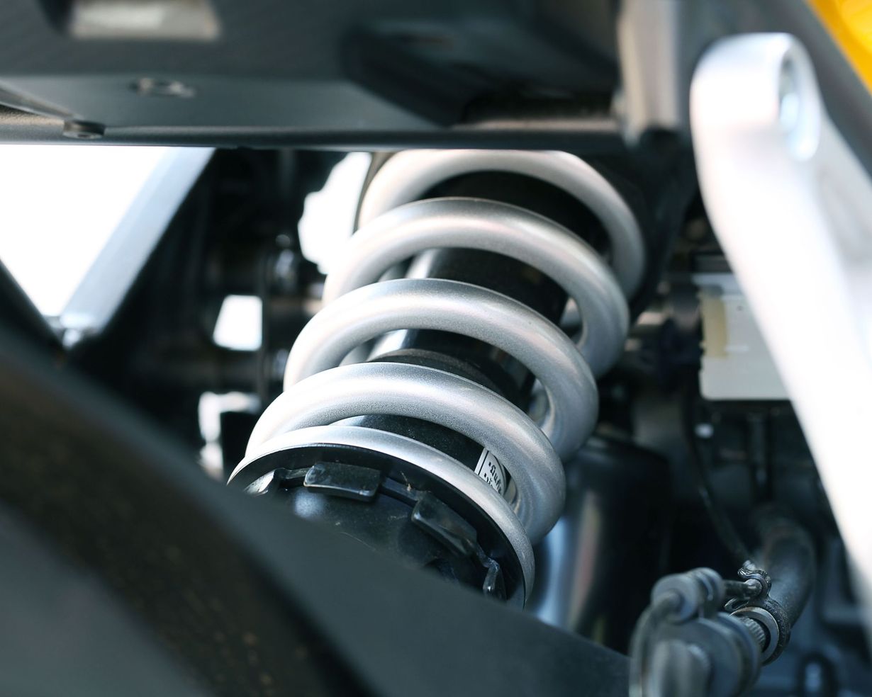 Close-up of a white coil spring suspension inside a vehicle chassis.