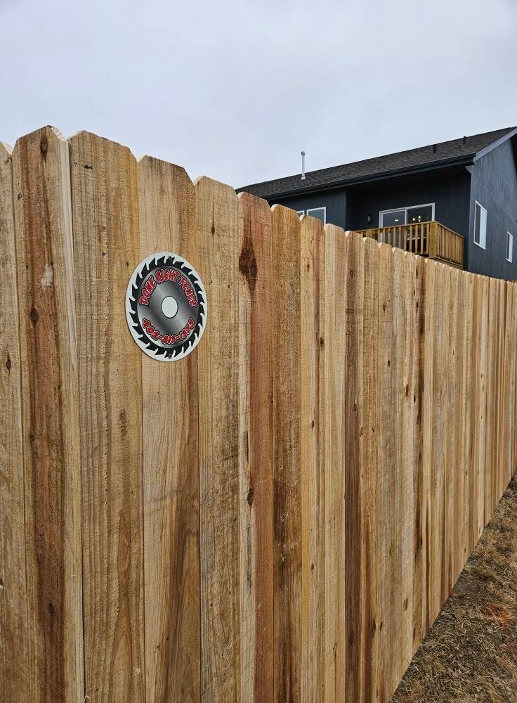 Wooden fence with a circular sign mounted on the left side, beside a dark house.