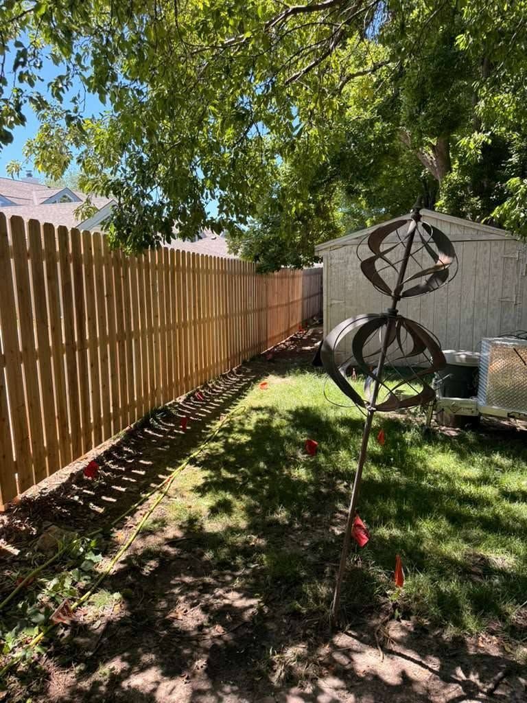 Backyard with wooden fence, tree shade, lawn, and a metal garden spinner sculpture