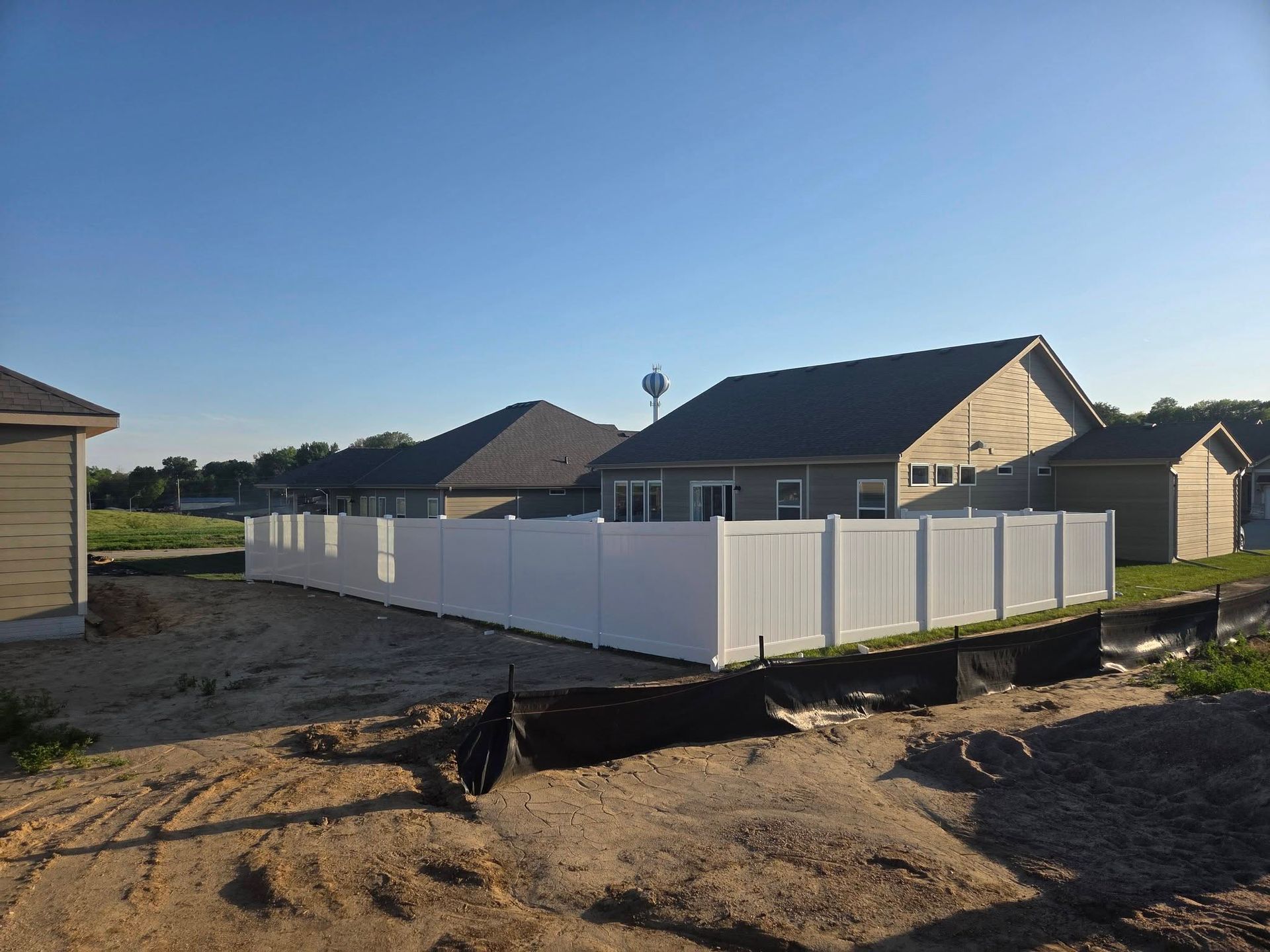 White vinyl fence around a new house in a suburban lot at sunset