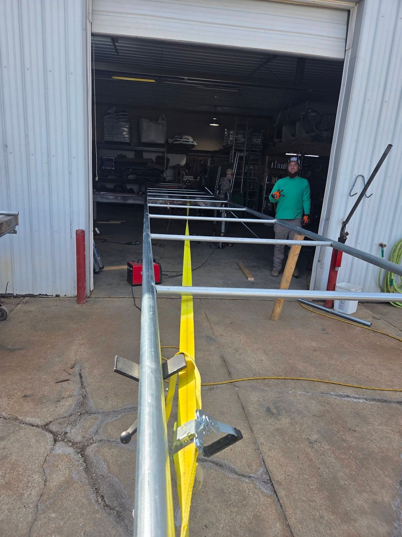 Yellow safety barrier at warehouse doorway, with a worker standing inside the open bay.