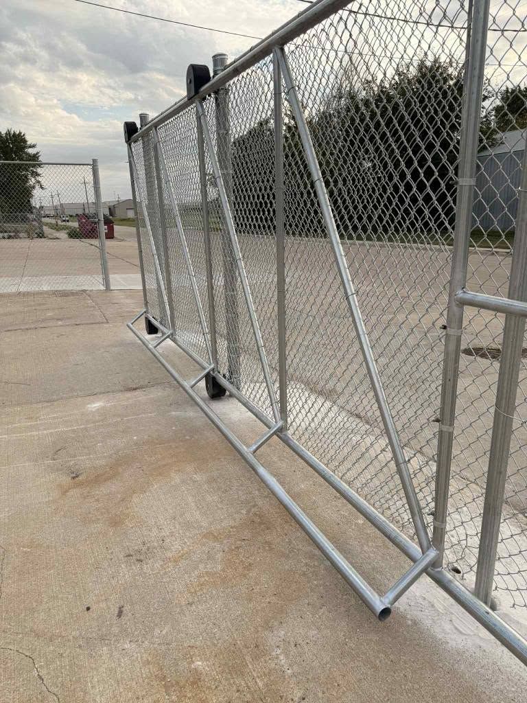 Bent chain-link fence panel leaning on a concrete lot under a cloudy sky