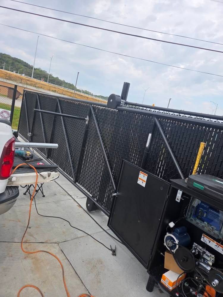 Black metal barricade panels on a concrete lot beside a truck and utility equipment.